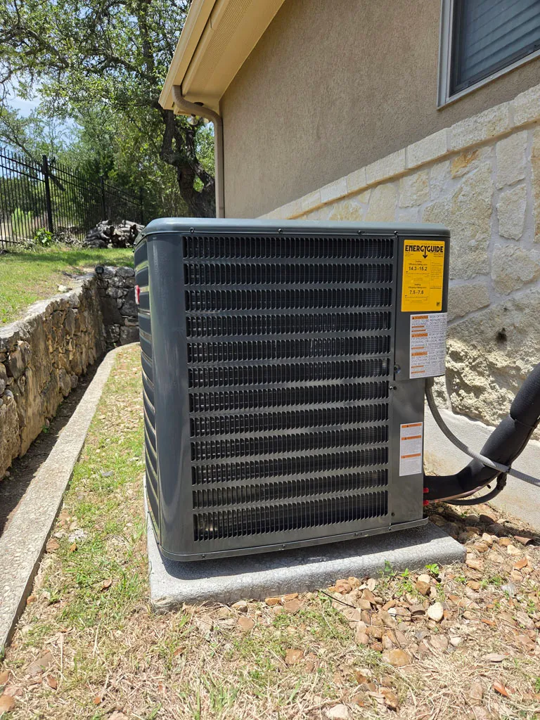 Outdoor AC condenser install on stone-skirted San Antonio home